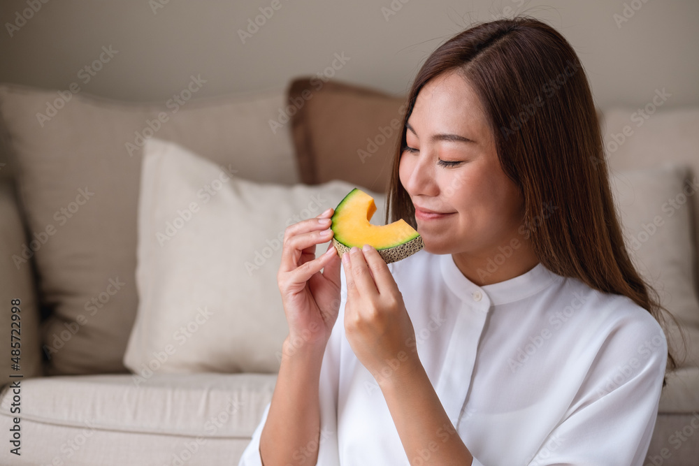 Portrait image of a young woman holding and eating a piece of Cantaloupe melon Portrait image of a young woman holding and eating a piece of Cantaloupe melon