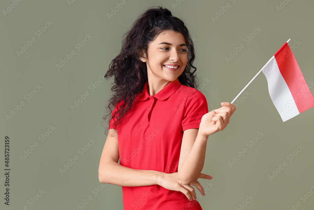 Smiling Asian woman with flag of Indonesia looking aside on color background Smiling Asian woman with flag of Indonesia looking aside on color background