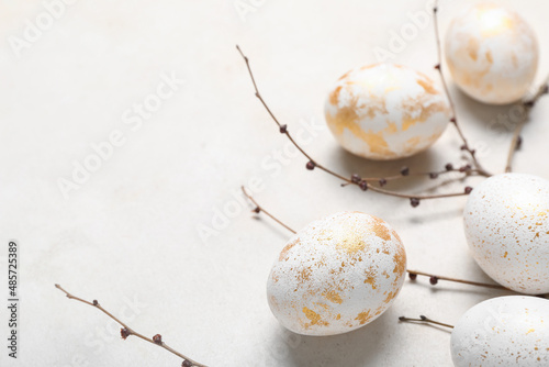 Beautiful Easter eggs and tree branches on light background, closeup