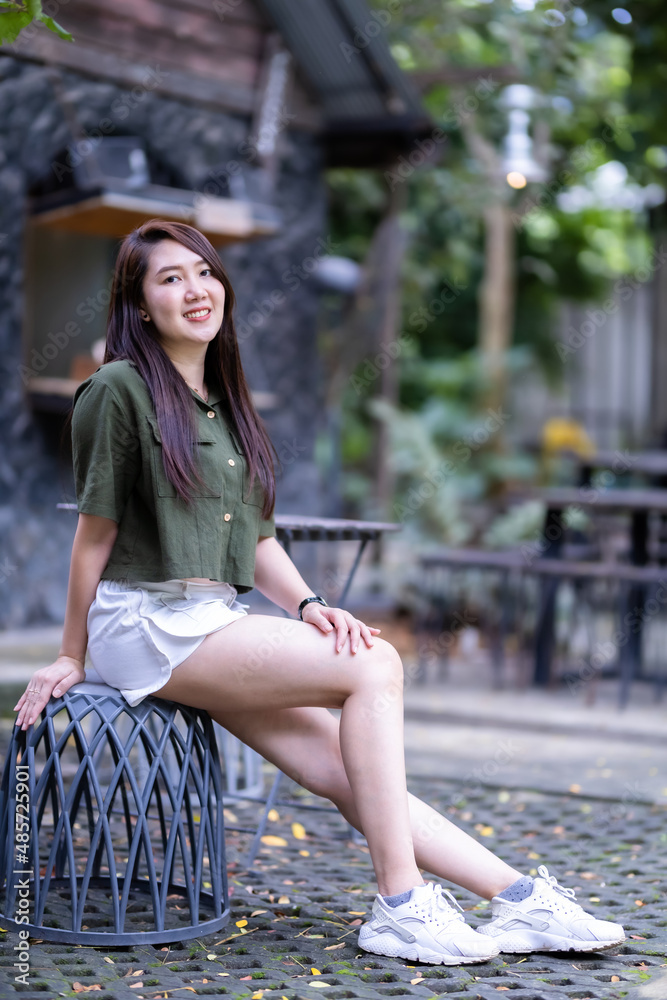 a portrait of beautiful happy asian woman traveler wearing brownish green dress stylish hipster Summer sunny lifestyle on the street outdoors at sunny summer day in park background