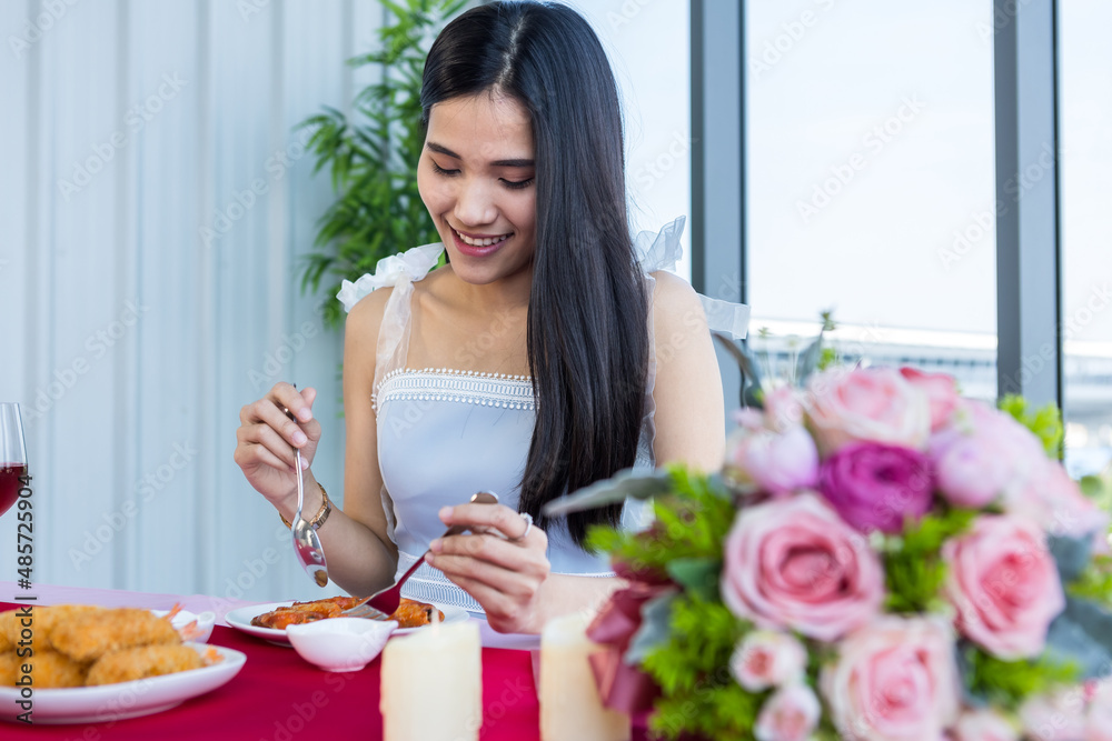 Valentine's day concept, Asian young girl sitting at a table food with wine glasses and bouquet of red and pink roses wine and waiting for her man at in the restaurant background Valentine's day concept, Asian young girl sitting at a table food with wine glasses and bouquet of red and pink roses wine and waiting for her man at in the restaurant background