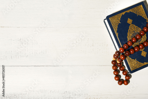 Koran and Muslim prayer beads on white wooden background photo
