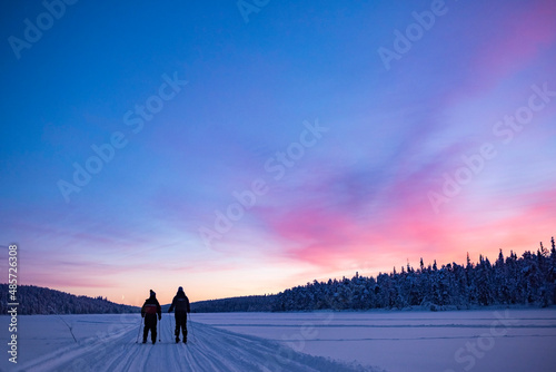 Bild auf Leinwand Skiing on the frozen lake at Torassieppi at sunset, Lapland, Finland