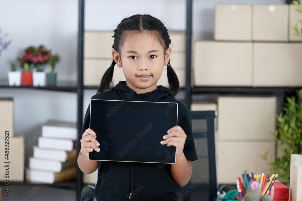 Portrait shot of Asian young primary schoolgirl in casual outfit standing smiling holding showing black blank screen monitor touchscreen tablet computer in hands for advertising copy space and text Portrait shot of Asian young primary schoolgirl in casual outfit standing smiling holding showing black blank screen monitor touchscreen tablet computer in hands for advertising copy space and text