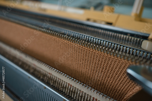 Knitted fabric in warm caramel beige on a knitting machine
