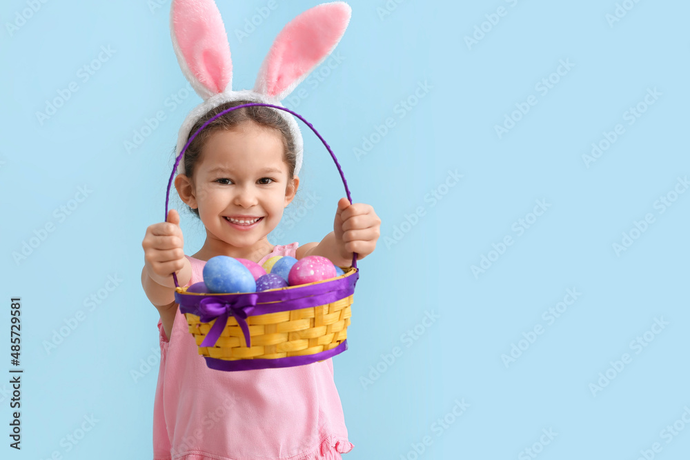 Funny little girl with bunny ears and Easter basket on blue background Funny little girl with bunny ears and Easter basket on blue background