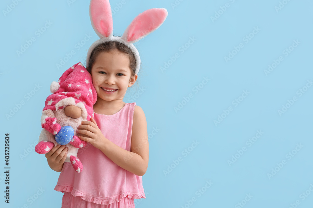 Funny little girl with bunny ears and toy on blue background. Easter celebration Funny little girl with bunny ears and toy on blue background. Easter celebration