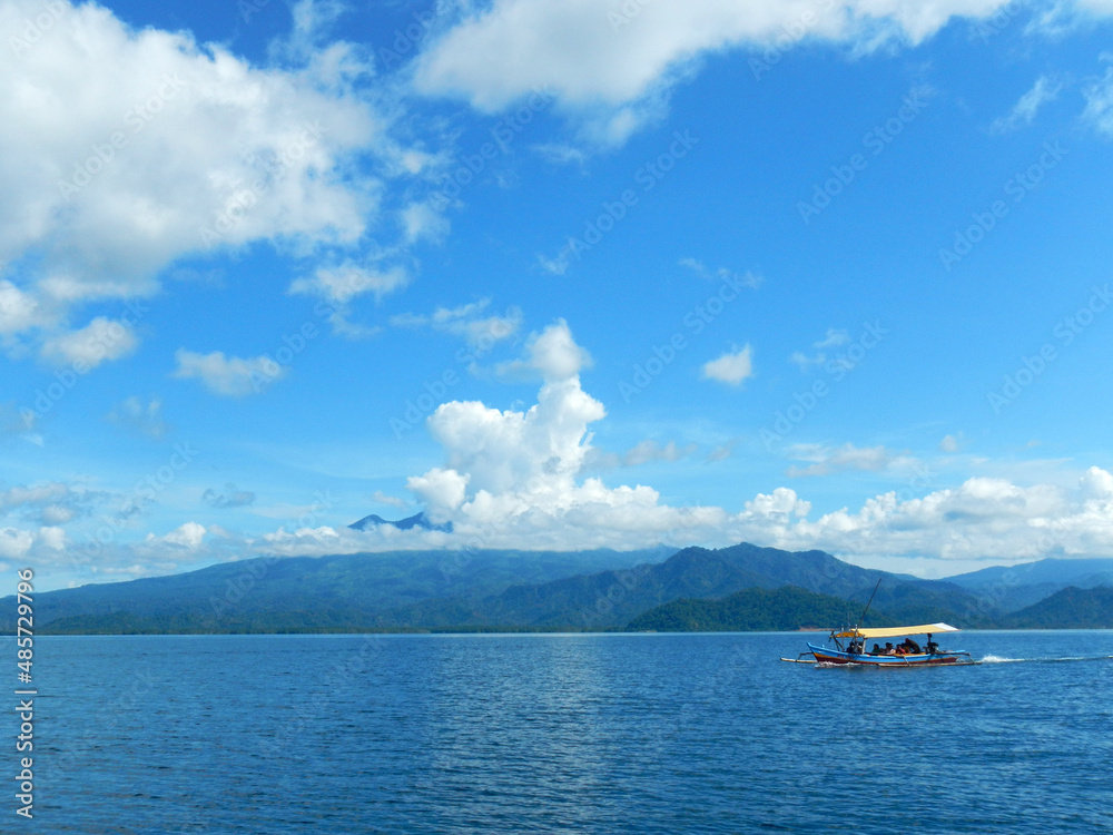 Wooden ship sailing on blue sea with island and blue sky background Wooden ship sailing on blue sea with island and blue sky background