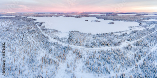 Fototapeta Naklejka Na Ścianę i Meble -  Aerial of Snow covered lake and forest winter landscape showing amazing Lapland scenery in Scandinavia in Finland drone