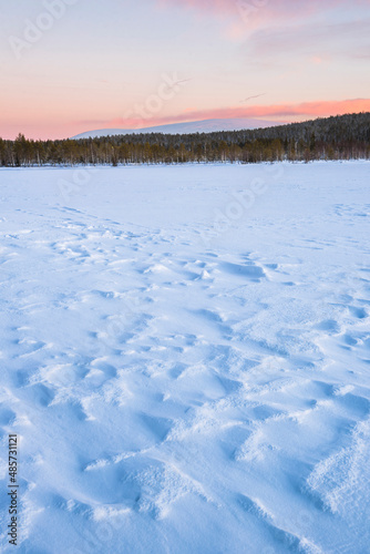 Frozen snow covered lake in the winter landscape in Lapland at sunset inside the Arctic Circle in Finland
