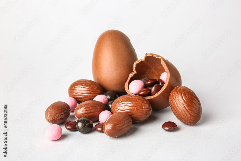 Obraz premium Different chocolate Easter eggs and delicious candies on light background