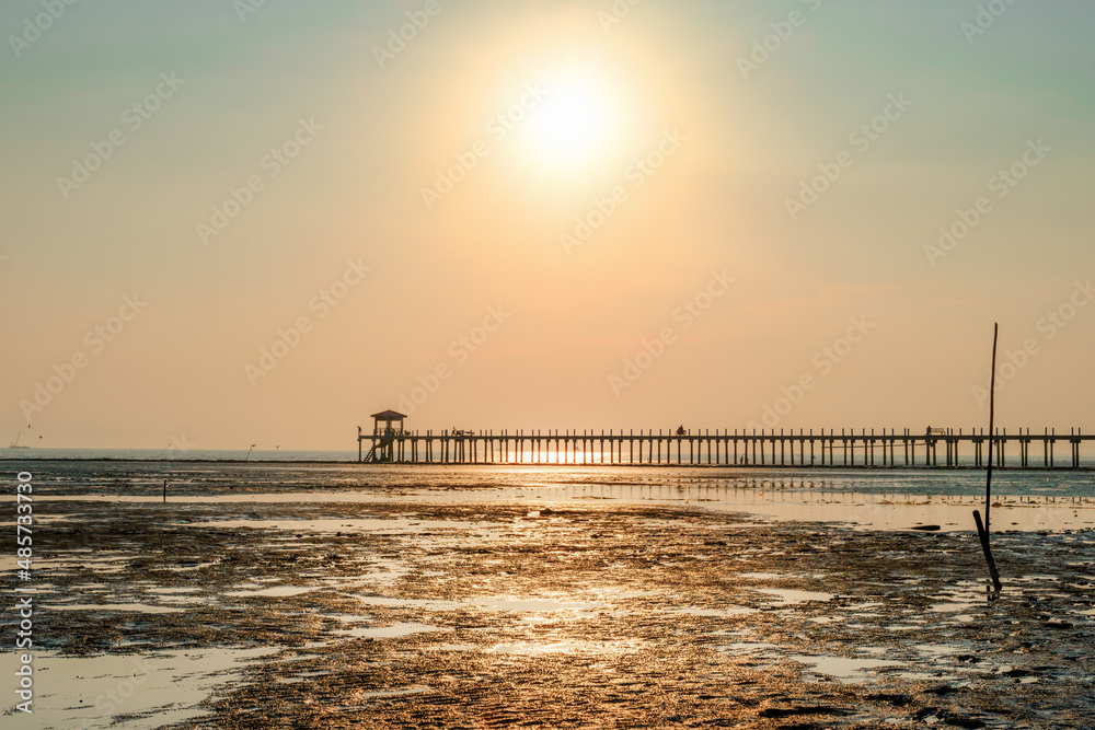 wetland after low tide sea with silhouette pier over sunset sky