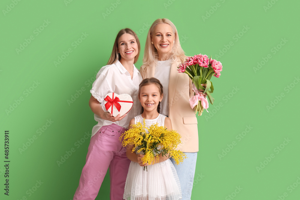 Young woman with her little daughter, mother and gifts on green background. International Women's Day Young woman with her little daughter, mother and gifts on green background. International Women's Day