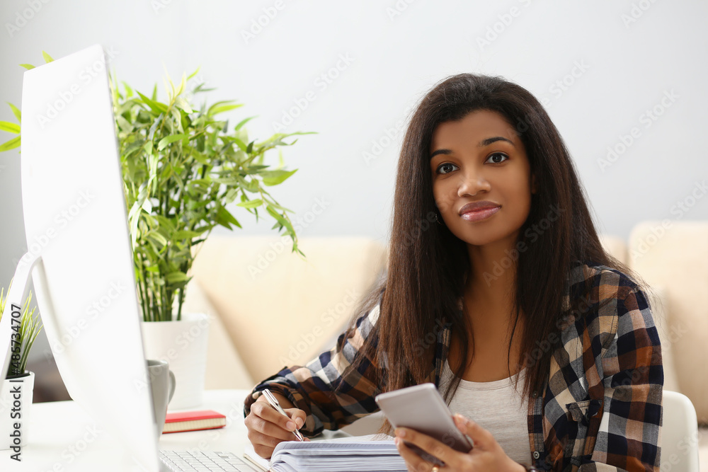 Lovely latin woman on workplace, write in notebook, computer device on desk Lovely latin woman on workplace, write in notebook, computer device on desk