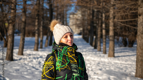 A girl in a winter down jacket on the background of a winter forest.