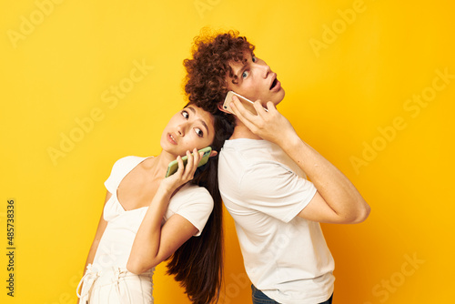 young couple talking on the phone yellow technology background