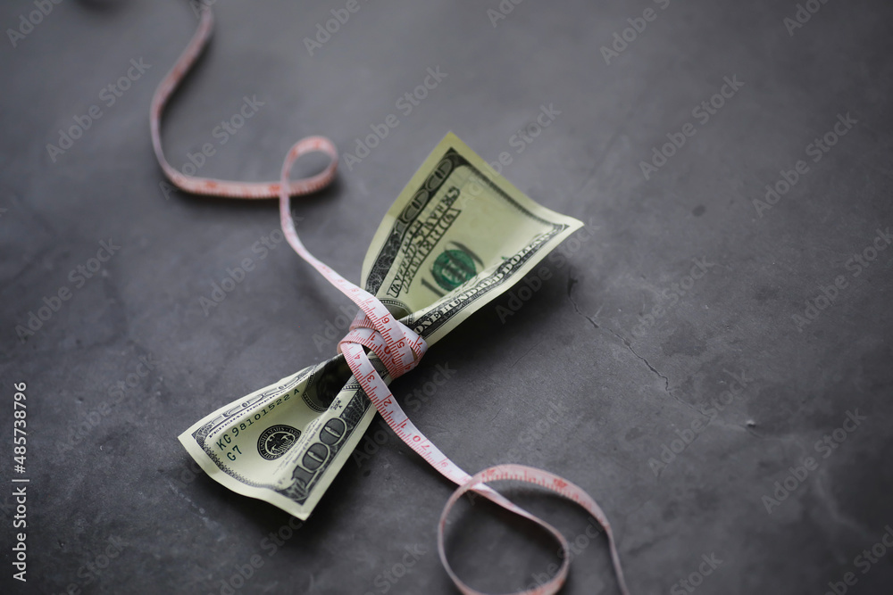 Business concept. The depreciation of the national currency. Hundred dollar bill. Inflation and stagnation. Tighten the hundred dollar bill with a measuring chain. Business concept. The depreciation of the national currency. Hundred dollar bill. Inflation and stagnation. Tighten the hundred dollar bill with a measuring chain.
