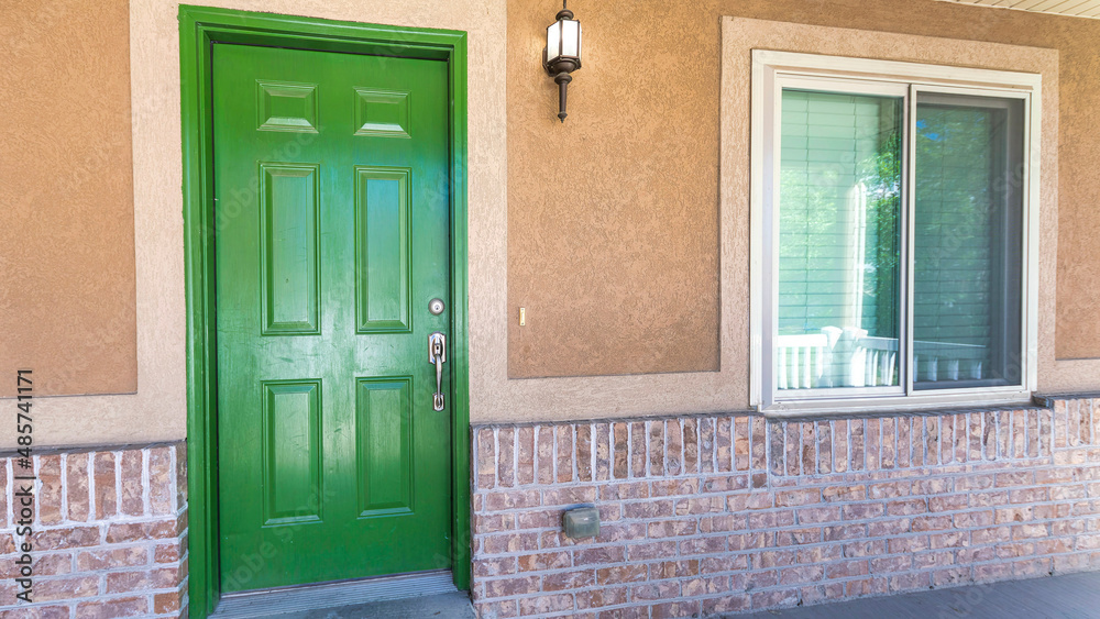 Panorama Front porch of a house with green wooden front door and wall lamp Panorama Front porch of a house with green wooden front door and wall lamp