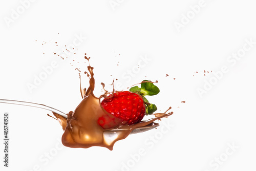 Strawberry falling on a spoon with chocolate
