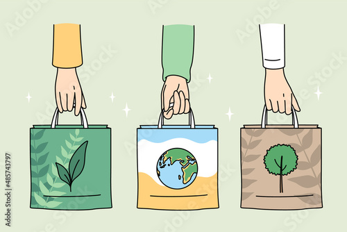 Ecology care and eco-friendly things concept. Human hands holding eco-friendly bags with pictures of plant planet and tree vector illustration 