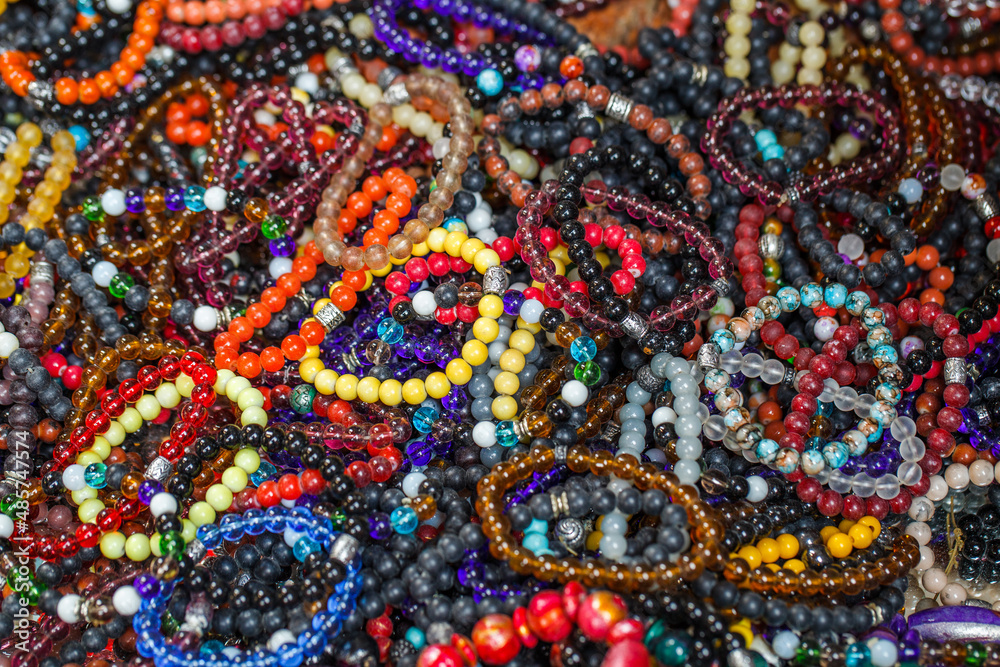 Bracelets made of multi colored beads on a string, in bulk, selective focus.