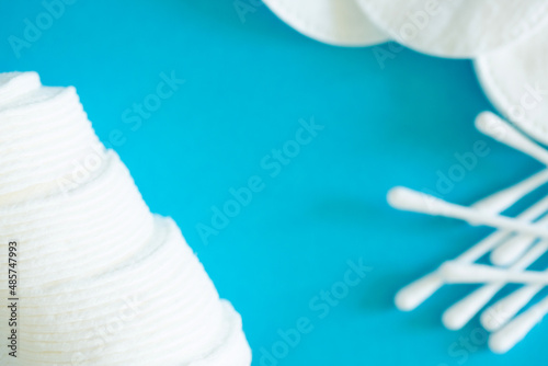 Cotton pads and ear sticks for hygiene on a blue background. The concept of clean face and body. Bath amenities for hygiene. Flat layout with copy space.