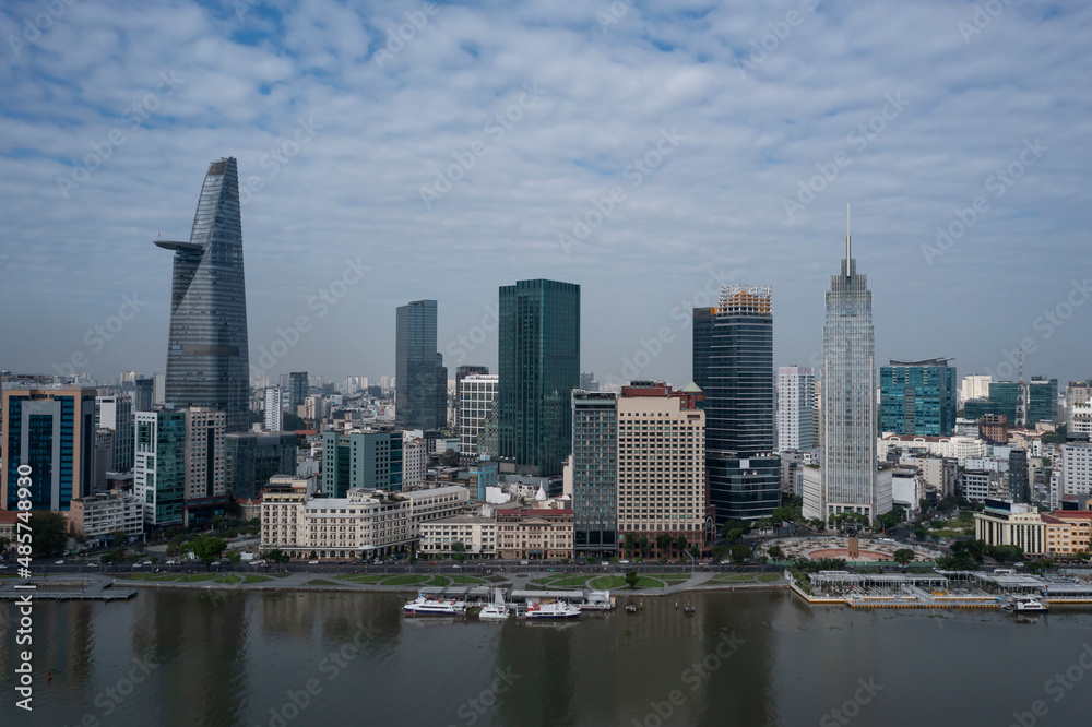Drone panorama view of Ho Chi Minh City center featuring skyline and newly completed waterfront redevelopment along the Saigon river on sunny morning.