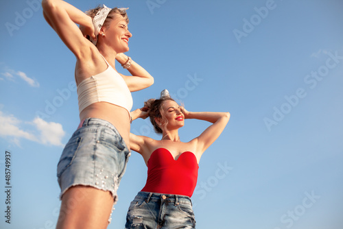 The portrait of woman wearing summer clothes posing against blue sky