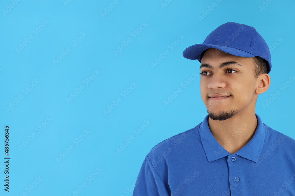 Young man in delivery uniform on blue background Young man in delivery uniform on blue background