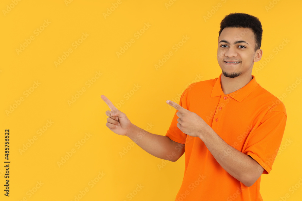 Young man in orange polo on yellow background Young man in orange polo on yellow background