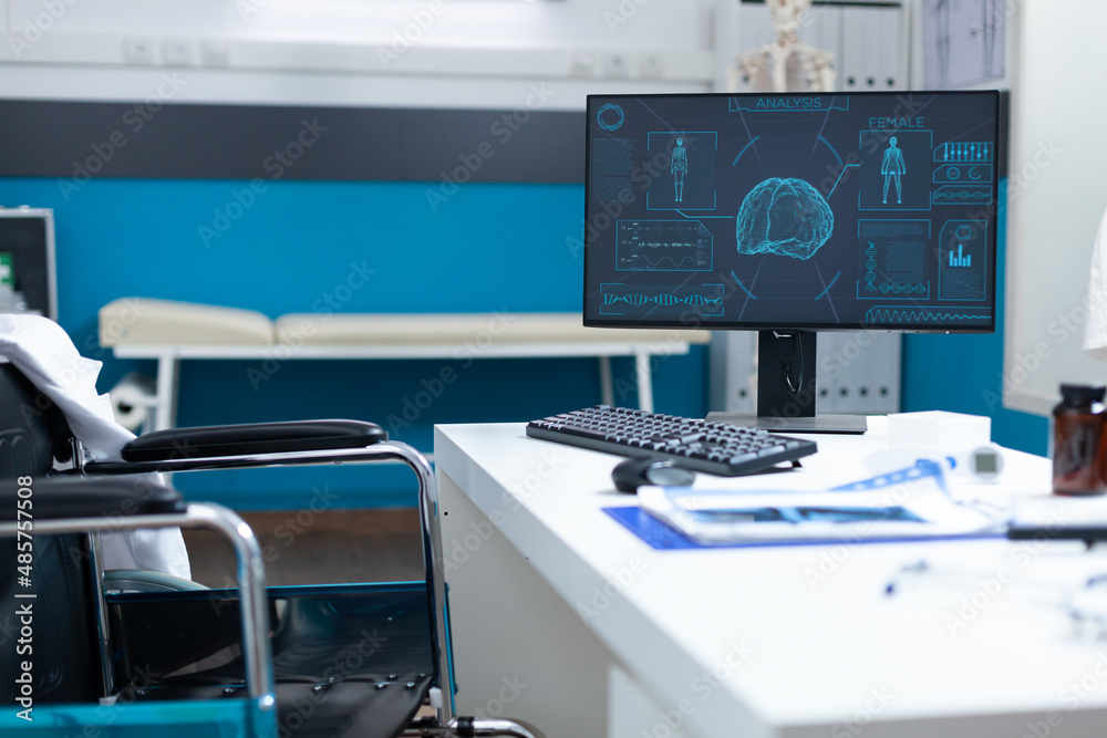 Empty bright hospital office room equipped with medical examination equipment ready for patient consultation. Computer standing on table having human body skeleton on screen. Medicine concept