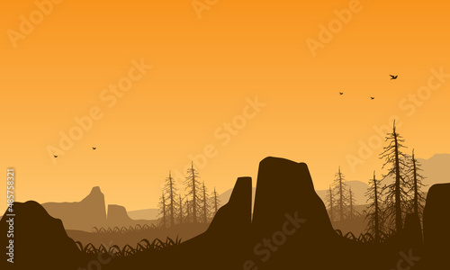 Realistic mountain view of the countryside at dusk with dry tree silhouettes and high cliffs