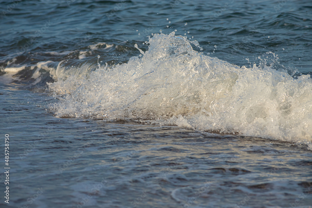Fototapeta premium Sea waves crash against large rocks on the shore, forming large splashes
