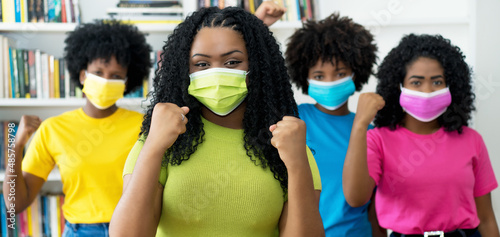 Happy african american woman with green face mask and group of female young adults © Daniel Ernst