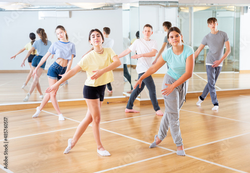 Teenagers in dance hall studying new movements, smiling and having fun