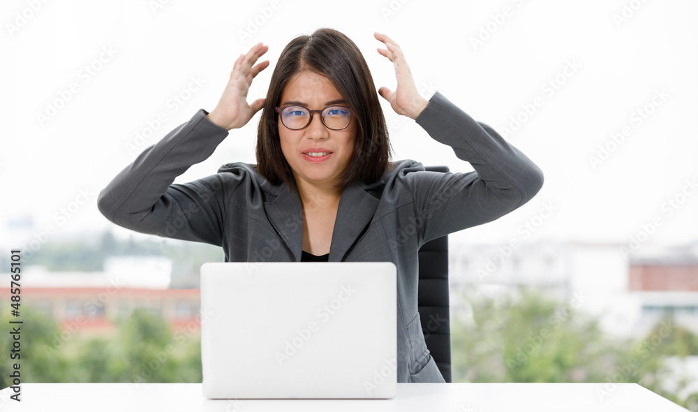 Asian angry stressed depressed female employee businesswoman secretary in formal suit hold hands on head have headache screaming shouting at work desk with laptop notebook computer in company office Asian angry stressed depressed female employee businesswoman secretary in formal suit hold hands on head have headache screaming shouting at work desk with laptop notebook computer in company office