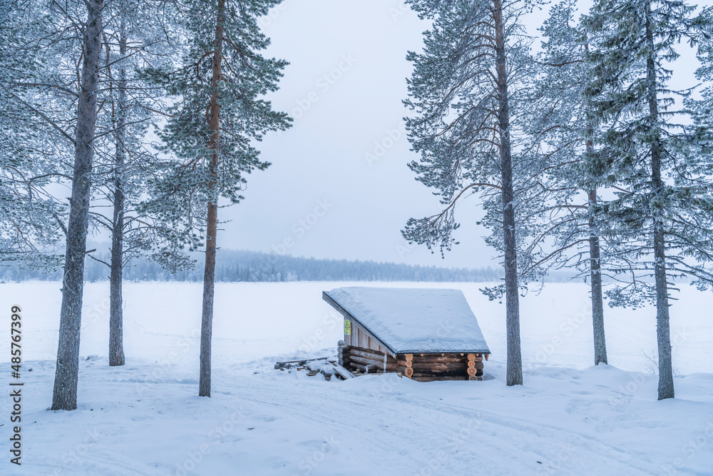 Wooden cabin hut in the forest for camping in a winter wonderland snow covered landscape in Lapland, Finland, Arctic Circle, Europe