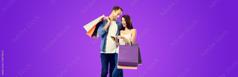 Love, holiday sales, shop, retail, consumer concept - happy smiling couple with shopping bags, and cellphone. Valentines Day holiday. Purple violet color background.