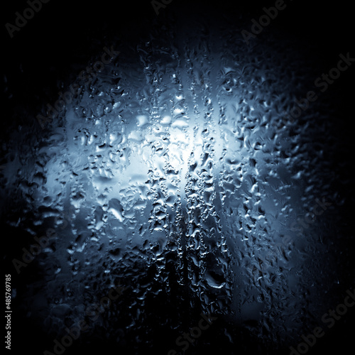 Close up image of wet glass in blue monochrome. Wet surface background.