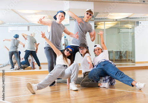 Positive teen girls and boys posing in dance studio during hip hop class