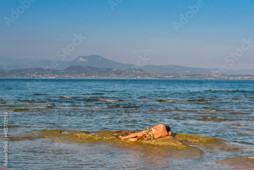 Mann faulenzt auf einem Stein am Gardasee, Italien © franzeldr