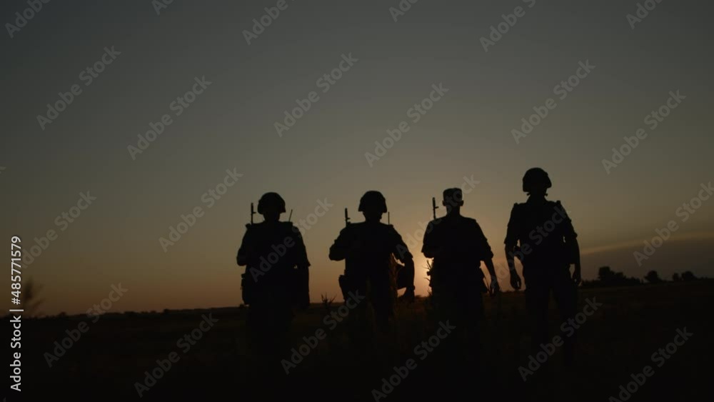 Two armed men with weapon walking across field after combat operation back view. Two armed men with weapon walking across field after combat operation back view.