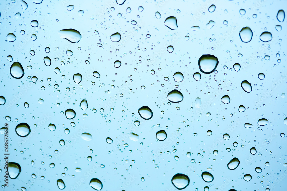Rain outside the window. Water droplets on a car glass on a background of blue sky and green grass. Overcast. Wet clean nature, ecology Rain outside the window. Water droplets on a car glass on a background of blue sky and green grass. Overcast. Wet clean nature, ecology