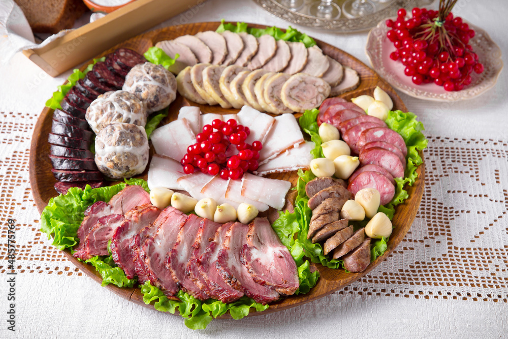 Cold cuts from homemade sausages, bacon, meat snacks, pastrami. National Moldavian, Romanian, or Ukrainian cuisine. Traditional dishes in an authentic interior.