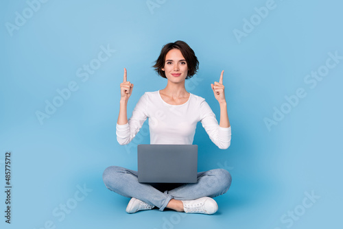 Photo of adorable funny woman wear white shirt legs crossed working modern gadget empty space isolated blue color background © deagreez