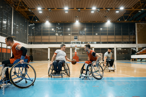 Athletes with disabilities playing wheelchair basketball match on sports court.
