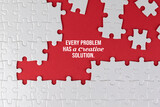 Inspirational motivational quote - Every problem has a creative solution. With white jigsaw puzzle with some missing pieces on red background. Business motivation words with puzzle jigsaw backgrounds.