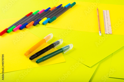 Set of color papers, scissors, ruler, felt-tip pens and pencil for creative work on multi-colored background. Top view