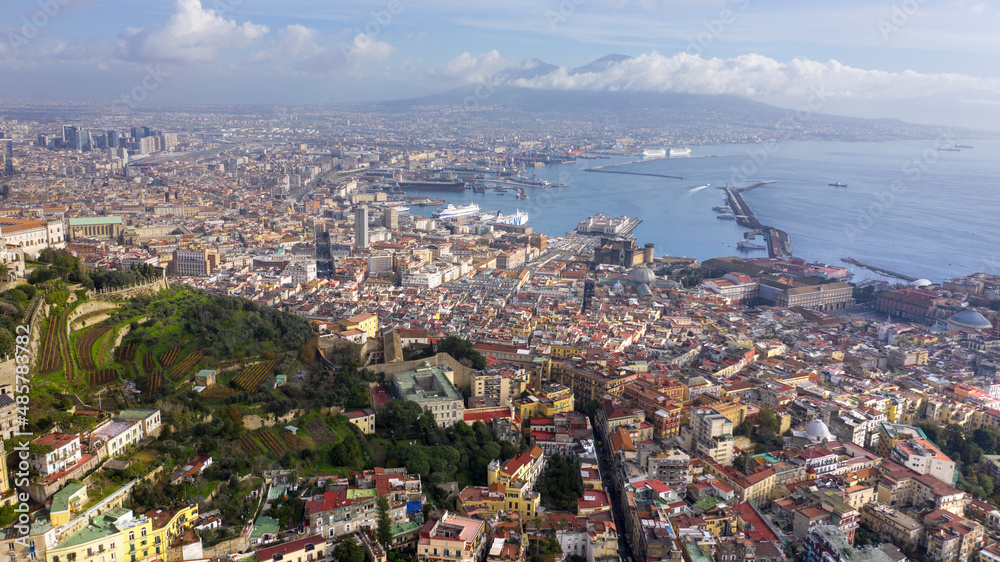 Fototapeta premium Aerial view of the city of Naples and the harbour on a sunny day. The volcano Vesuvius in the background.