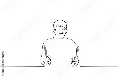 hungry man sitting at the table ready to eat and clutching a fork and knife - one line drawing vector. concept of insatiability, hunger, diet photo